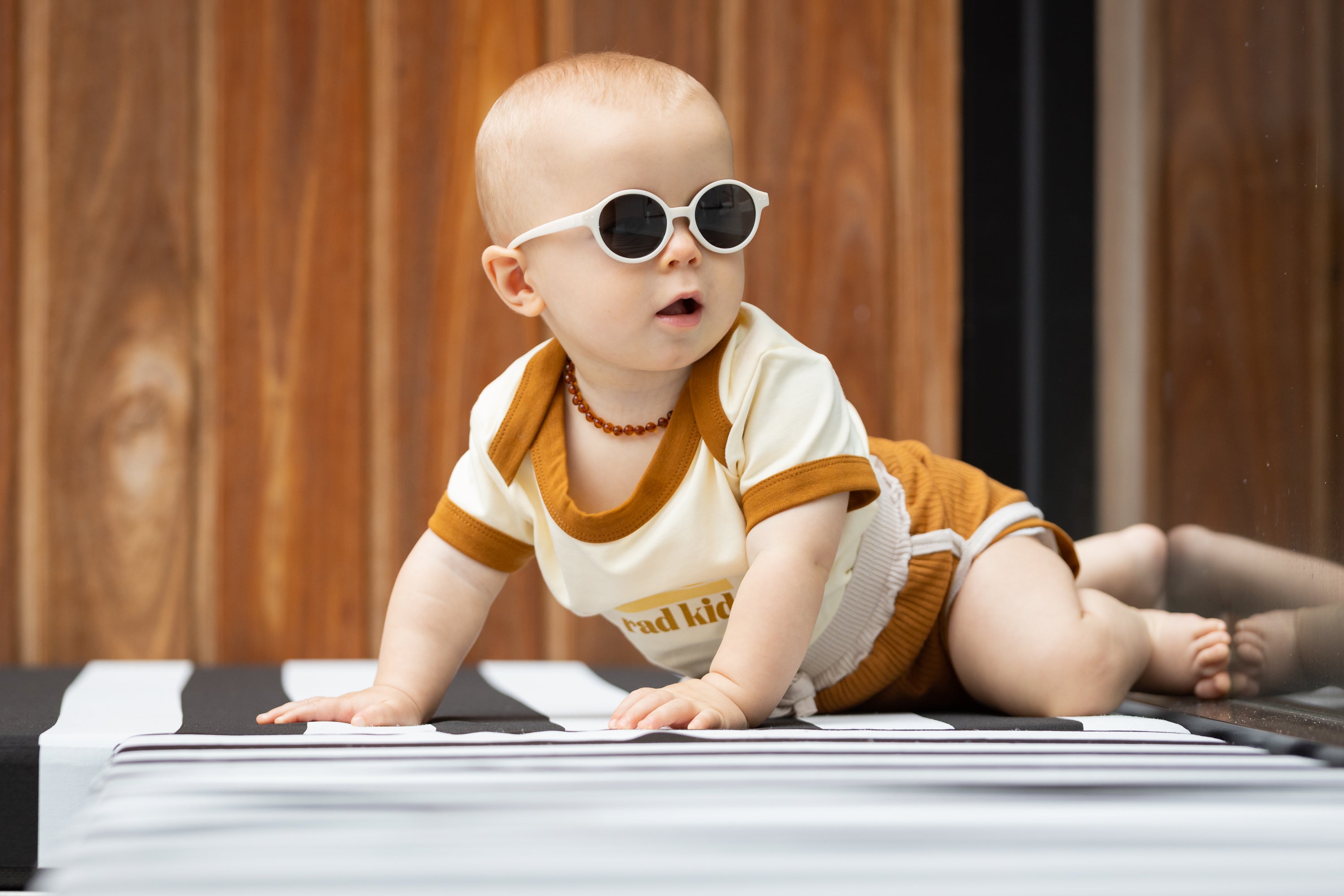 A cheeky little baby crawling around outisde while wearing Bukibaby Sunglasses